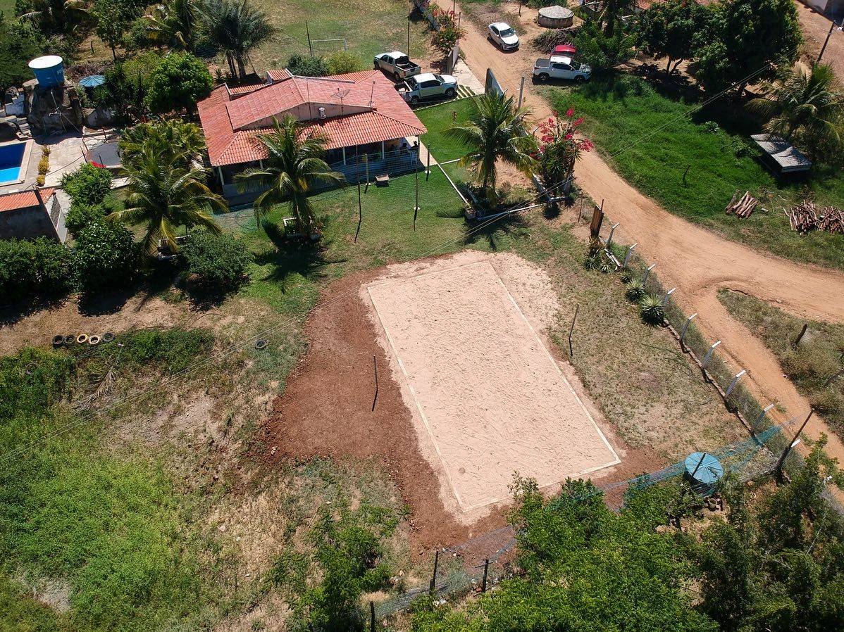 Vista aérea aproximada da casa, piscina e quadra de areia